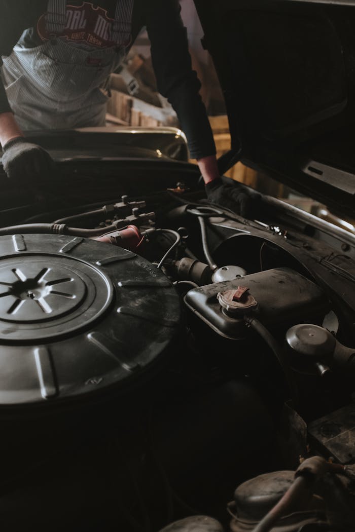 Close-up of a mechanic repairing a car engine in a garage setting.